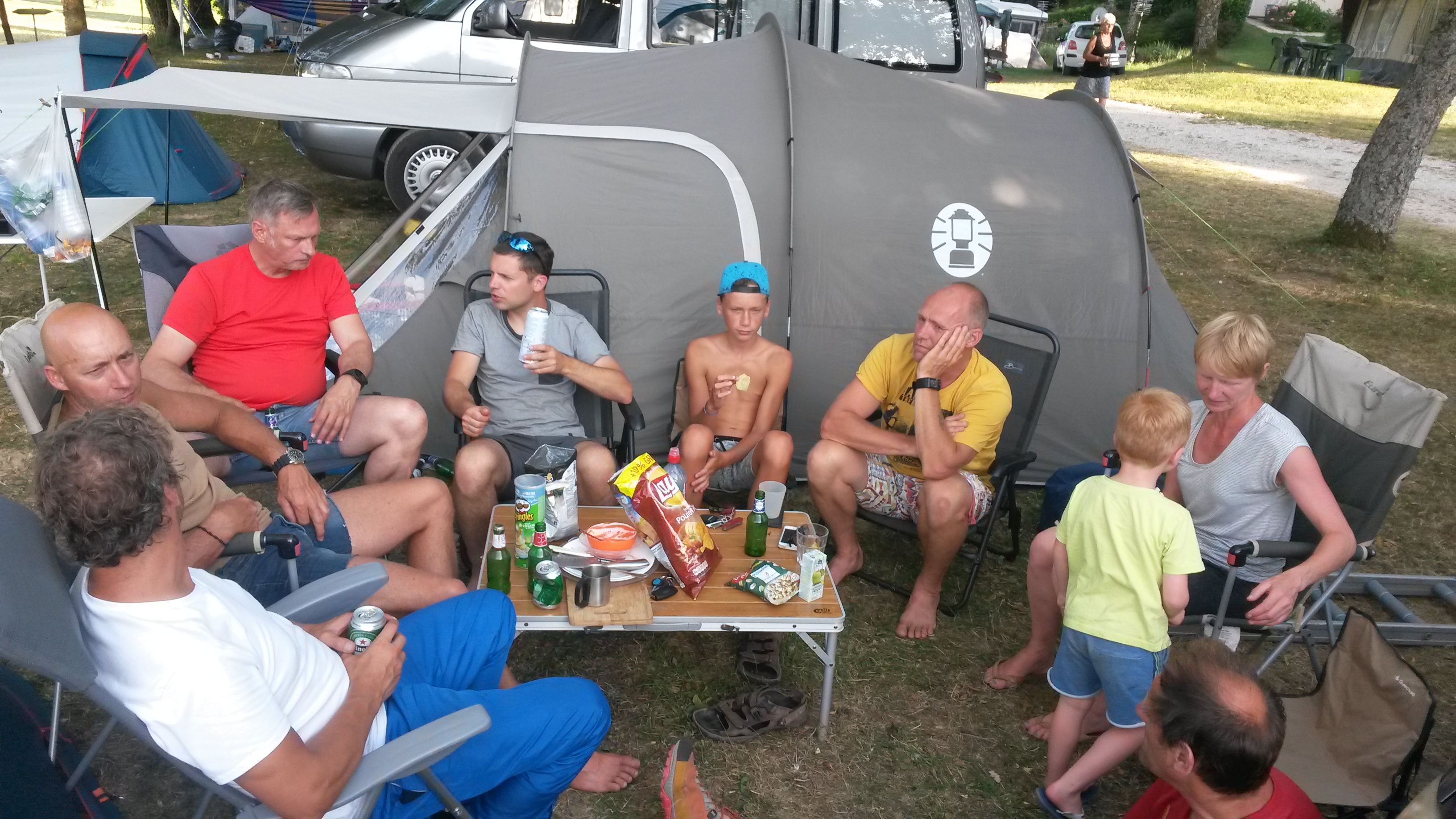 Een groep mensen op de camping rond een tafeltje met eten